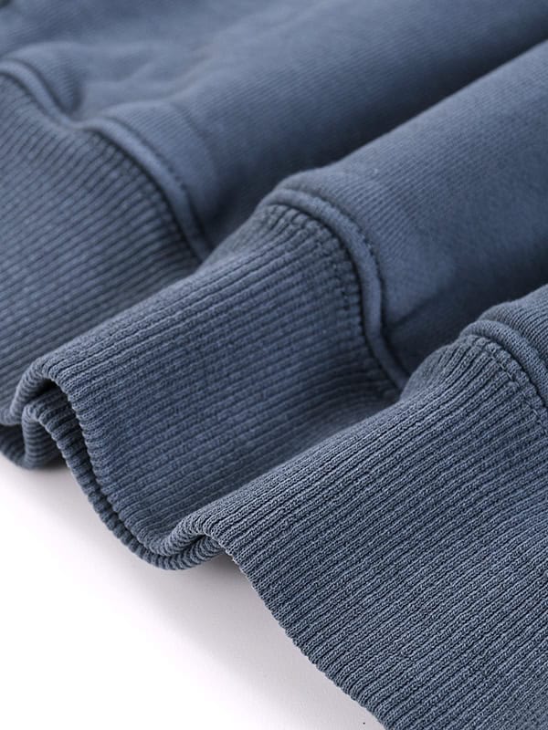 Close-up of a navy blue ribbed hoodie fabric, highlighting its texture and stitched cuffs.